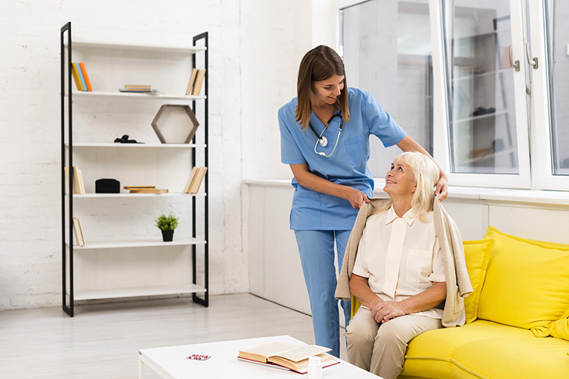long-shot-nurse-helping-old-woman-with-her-coat-min long-shot-nurse-helping-old-woman-with-her-coat-min